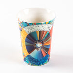 porcelain mug that features an illustration of a circle, radiant lines and abstract shapes with vibrant colours