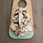 Toffee laid out on a board showing the nuts, as well as the white and milk chocolate swirl.