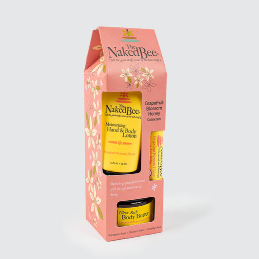 Set of three beauty and personal care items in a peach-coloured box. The items are yellow and arranged in three compartments. The product logo is located on the top of the box, and the front displays the collection name: Grapefruit Blossom Honey Collection.