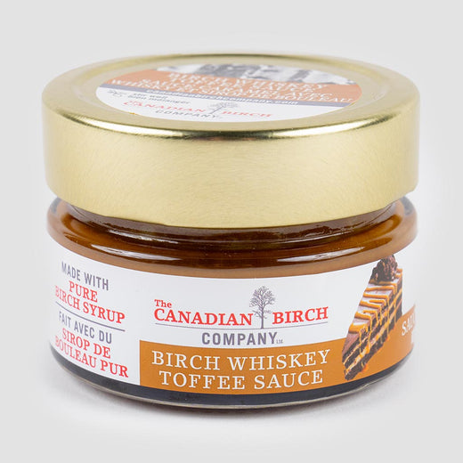 A small glass jar with a golden lid and a label that reads “Birch Whiskey Toffee Sauce.”