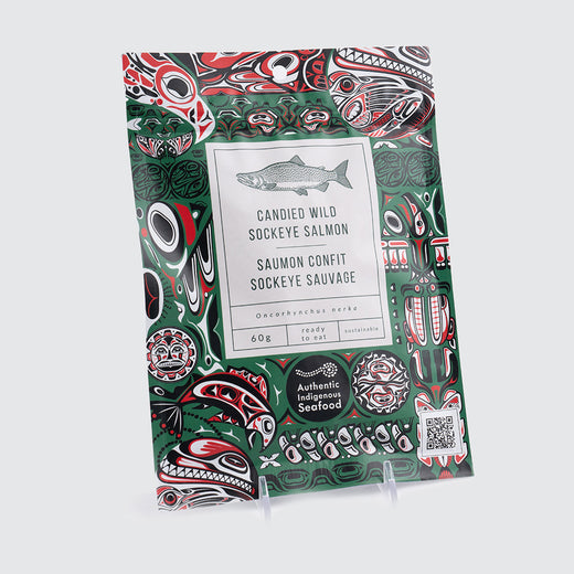 Green package featuring Indigenous Canadian illustrations in red, white and black depicting fish shapes. The centre label showcases a drawing of a salmon with the product name underneath.