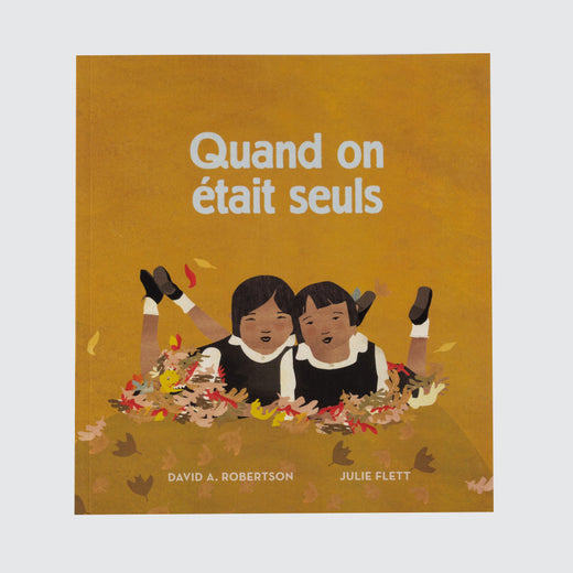 Book cover with the title “Quand on était seuls” Featuring two young people laying in leaves wearing uniforms.
