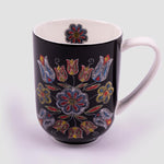 The front of the mug featuring the design. The exterior of the mug is all black with a red, green, yellow, blue, and white dotted floral pattern on either side. A small red, yellow, blue, and white dotted flower is on the inside of the lip of the mug.