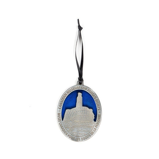 oval-shaped pewter-coloured ornament featuring an image of the CMHR against a blue sky 