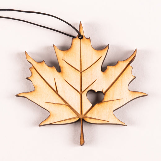 A laser-etched wooden ornament featuring a maple leaf with a heart cut-out 