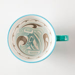 Interior of a turquoise mug featuring artwork of a killer whale