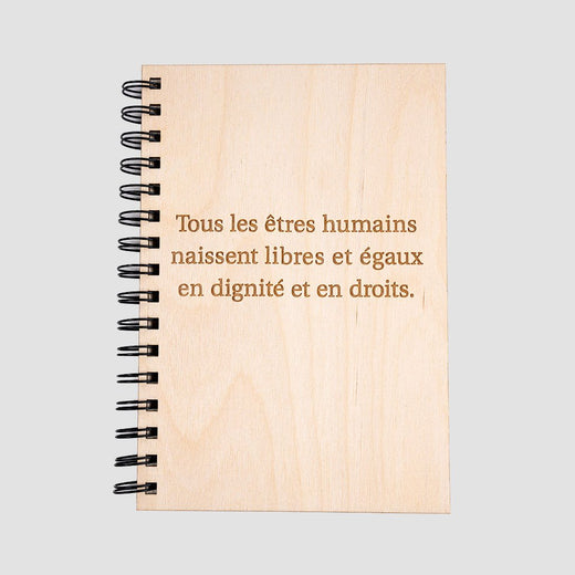 Wooden cover of journal with the quote “Tous les êtres humains naissent libres et égaux en dignité et en droits.”