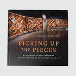 Book cover with the title “Picking up the Pieces”, with a photo of the Witness Blanket in the background.