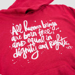 Close-up of white stylized script on red hoodie.