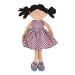 Rag doll with curly black hair, wearing a red and blue printed coton dress and blue shoes.