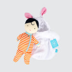 The cloth doll is placed on top and outside of the bunny sleep sack. It is dressed in orange striped pajamas with green detailing.
