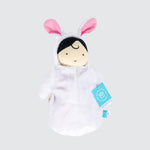 A cloth doll in a white bunny sleep sack. Only the doll’s light- skinned face and little bits of black hair can be seen.
