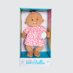 A light-skinned cloth doll with a brown ponytail on the top of its head. The doll is dressed in a pink and white dress with a matching soother.