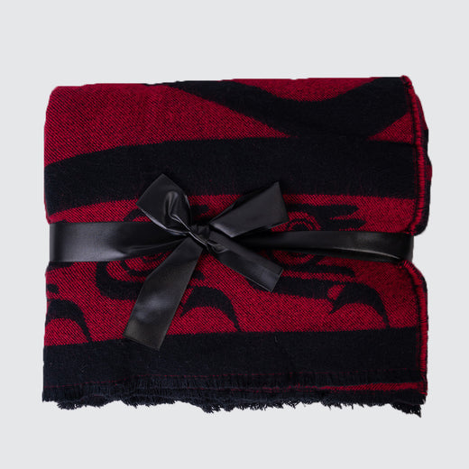 Red and black blanket laid flat. It is wrapped in a large black bow.